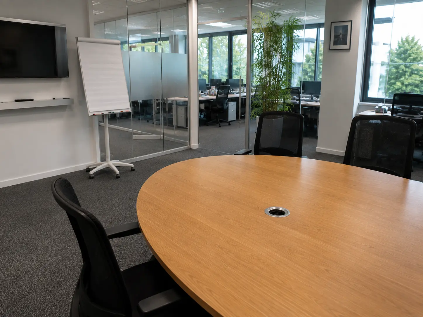 Heller Besprechungsraum mit langem Konferenztisch, Stühlen und Glaswand am Tag