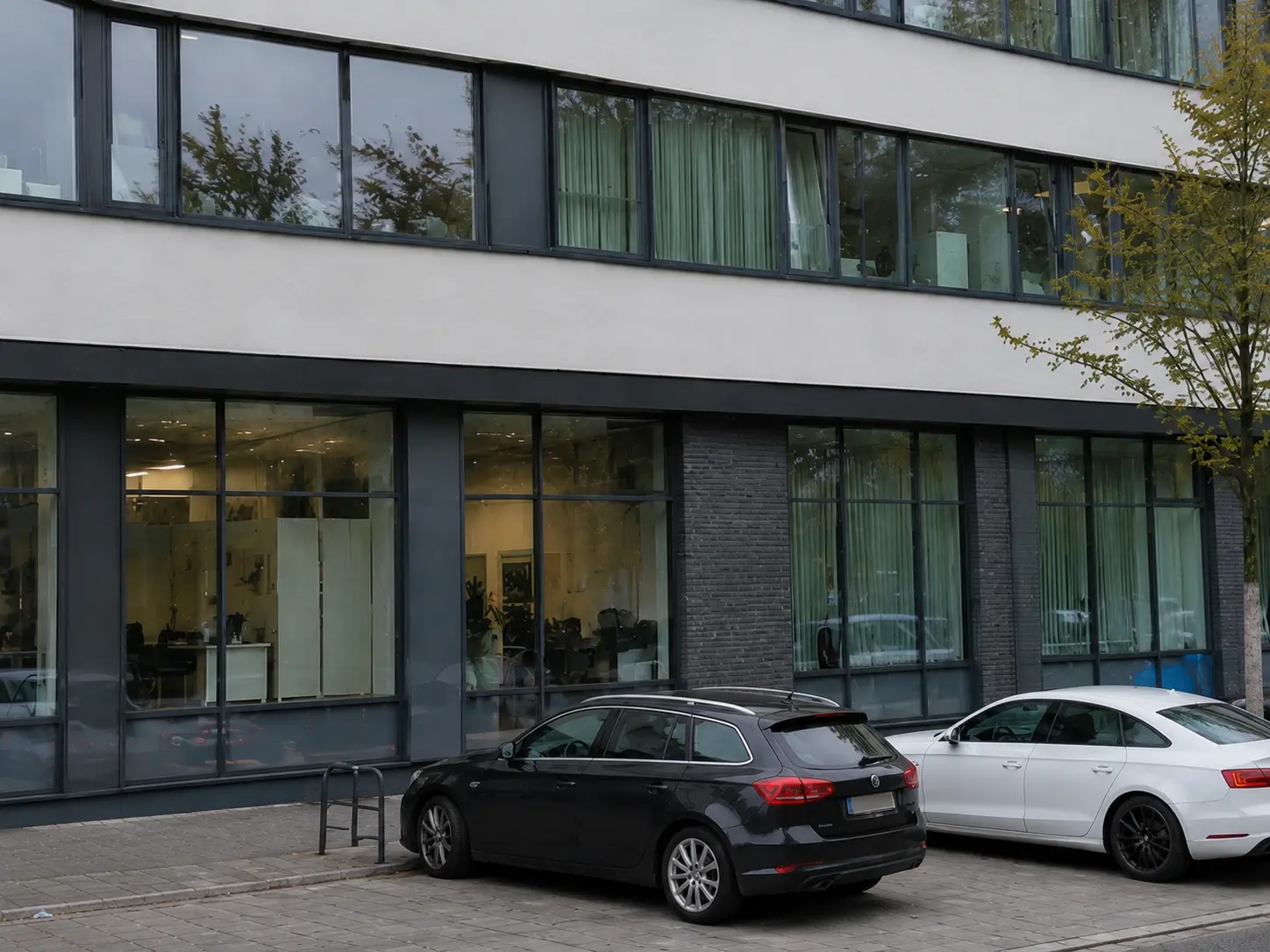 Bürogebäude mit heller Fassade, Glasfront und Stellplätzen, betreut mit Heizung, Aufzug und Lüftung