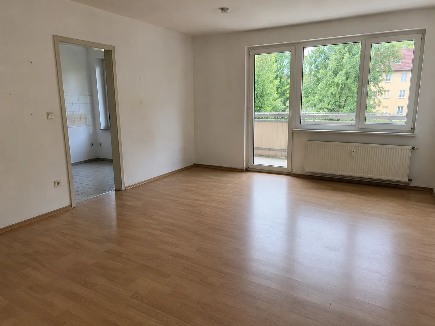 Leeres, gereinigtes Zimmer mit Holzboden und Balkontür nach dem Auszug