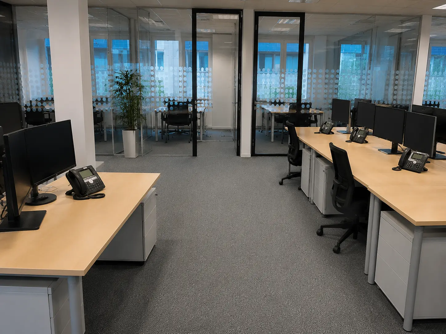 Gereinigtes Großraumbüro mit Schreibtischen, Monitoren und Teppichboden