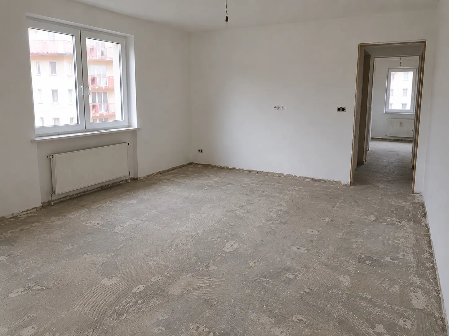 Leere Wohnung nach der Entrümpelung, der Boden ist noch staubig und die Wände sind frei