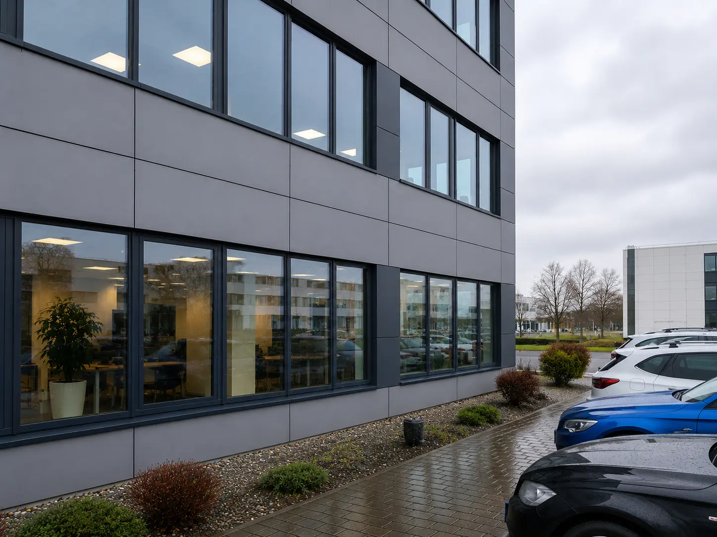 Frisch gereinigte Fensterfront eines Bürogebäudes, in den Scheiben spiegeln sich Himmel und Bäume